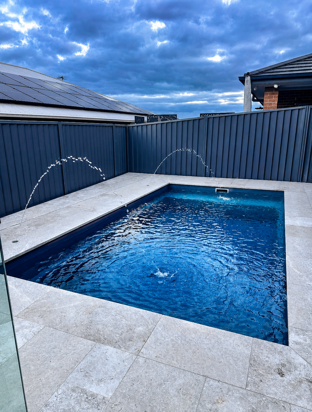 Fibreglass plunge pool with water-feature jets and travertine surround — Macarthur install